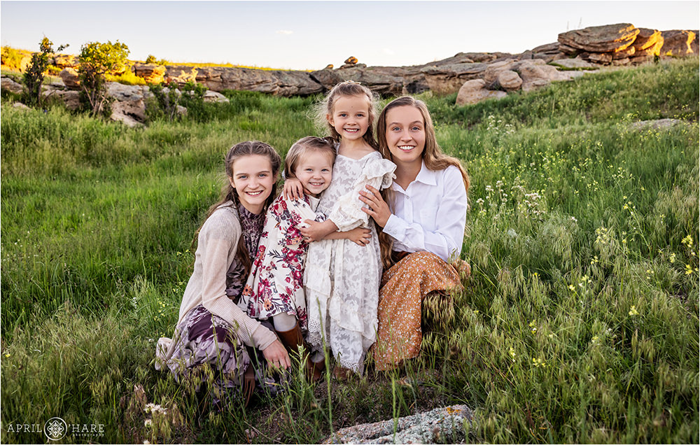Four sisters pose for a photo together in the wildflowers at their family farm in Franktown CO