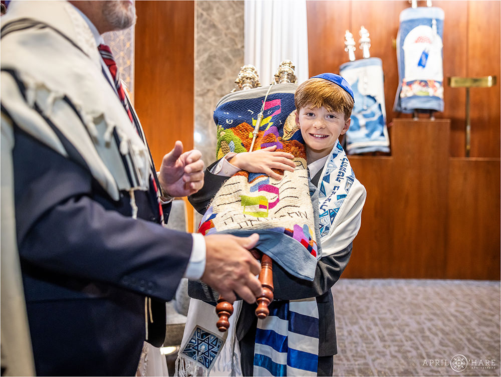 Bar Mitzvah boy holds the torah in his arms at his bar mitzvah rehearsal in Denver