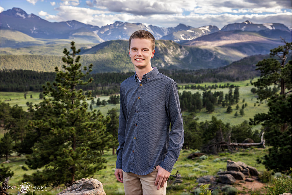 Senior wearing a Blue Button down shirt with a beautiful mountain backdrop inside of Rocky Mountain National Park in Estes Park Colorado