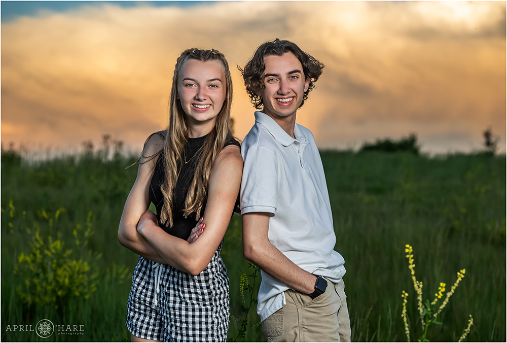 Brother and sister pose back to back with a pretty sunset sky in the backdrop at a private home in Aurora CO