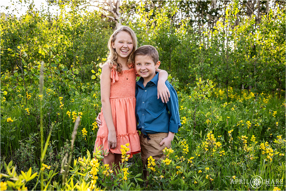 Siblings pose for a photo together in a yellow wildflower mountain meadow in Colorado