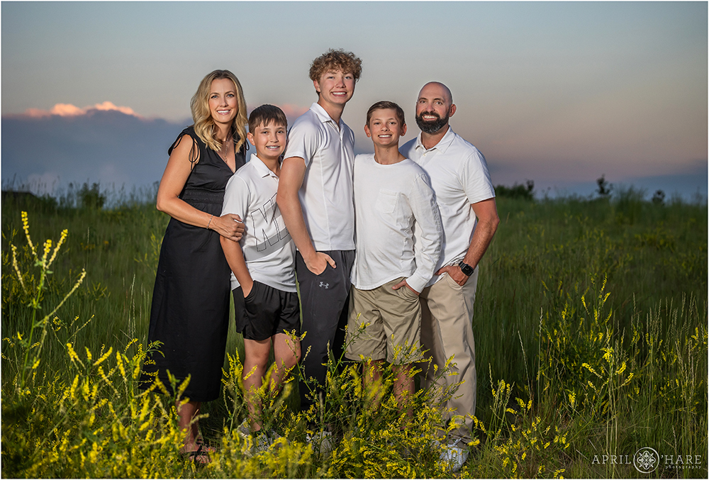 A beautiful family of 5 with 3 sons are photographed in the field full of wildflowers behind their home in Aurora Colorado