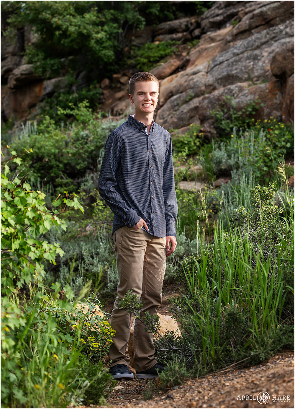 High school senior photo of a young man in the greenery with a rock backdrop in Estes Park Colorado