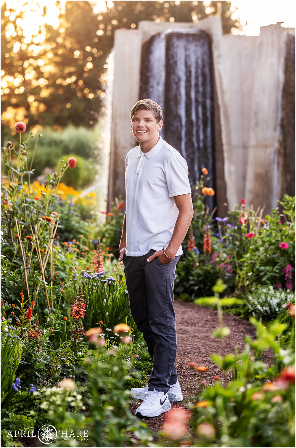 Senior photo in a colorful garden with a concrete fountain backdrop at Denver Botanic Gardens