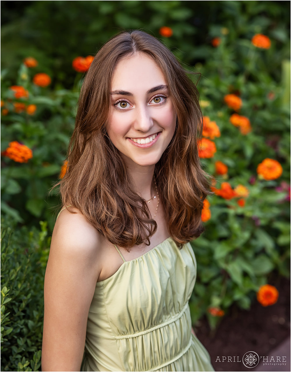 Beautiful orange floral backdrop for a high school senior girl wearing a light green outfit at Denver Botanic Gardens in Colorado