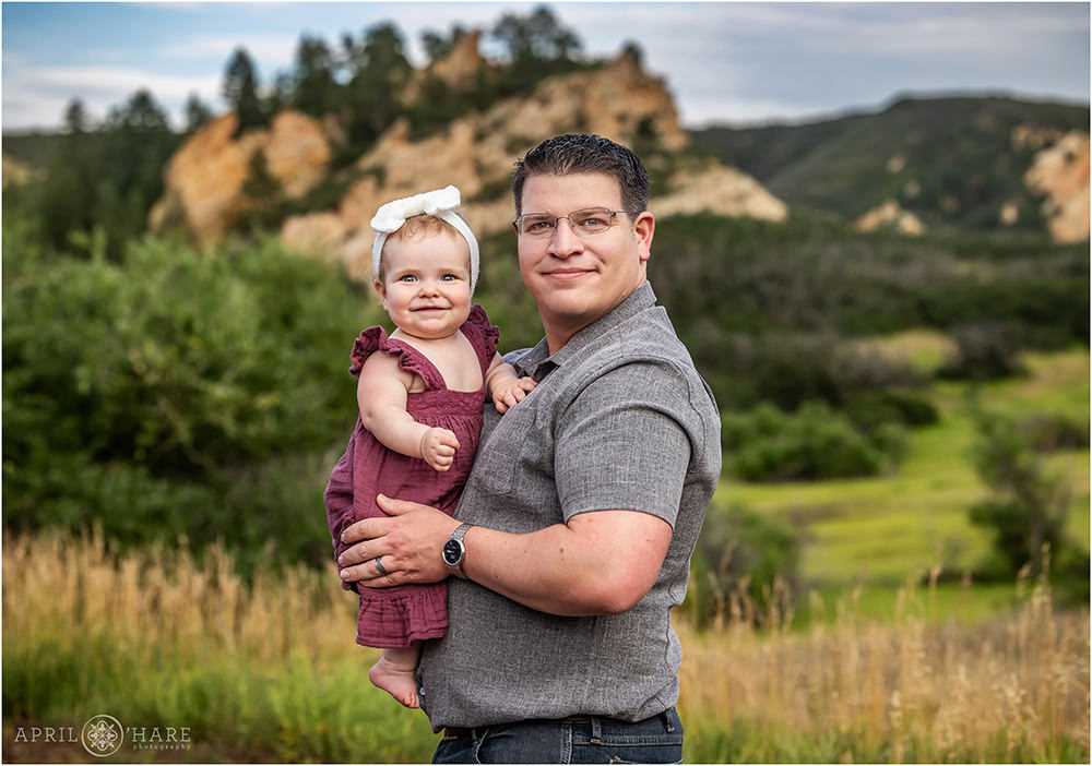 A father holds his baby girl in the pretty scenery of Roxborough State Park during summer in Colorado