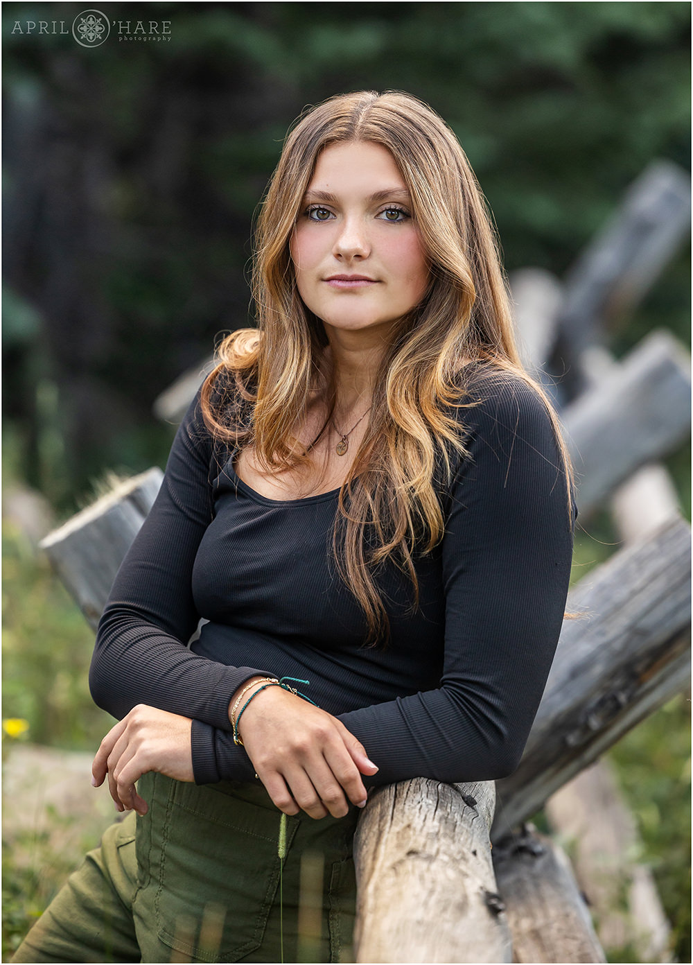 Gorgeous senior girl with a serious expression on her face wearing a black top with long sleeves at her senior portrait session in Evergreen CO