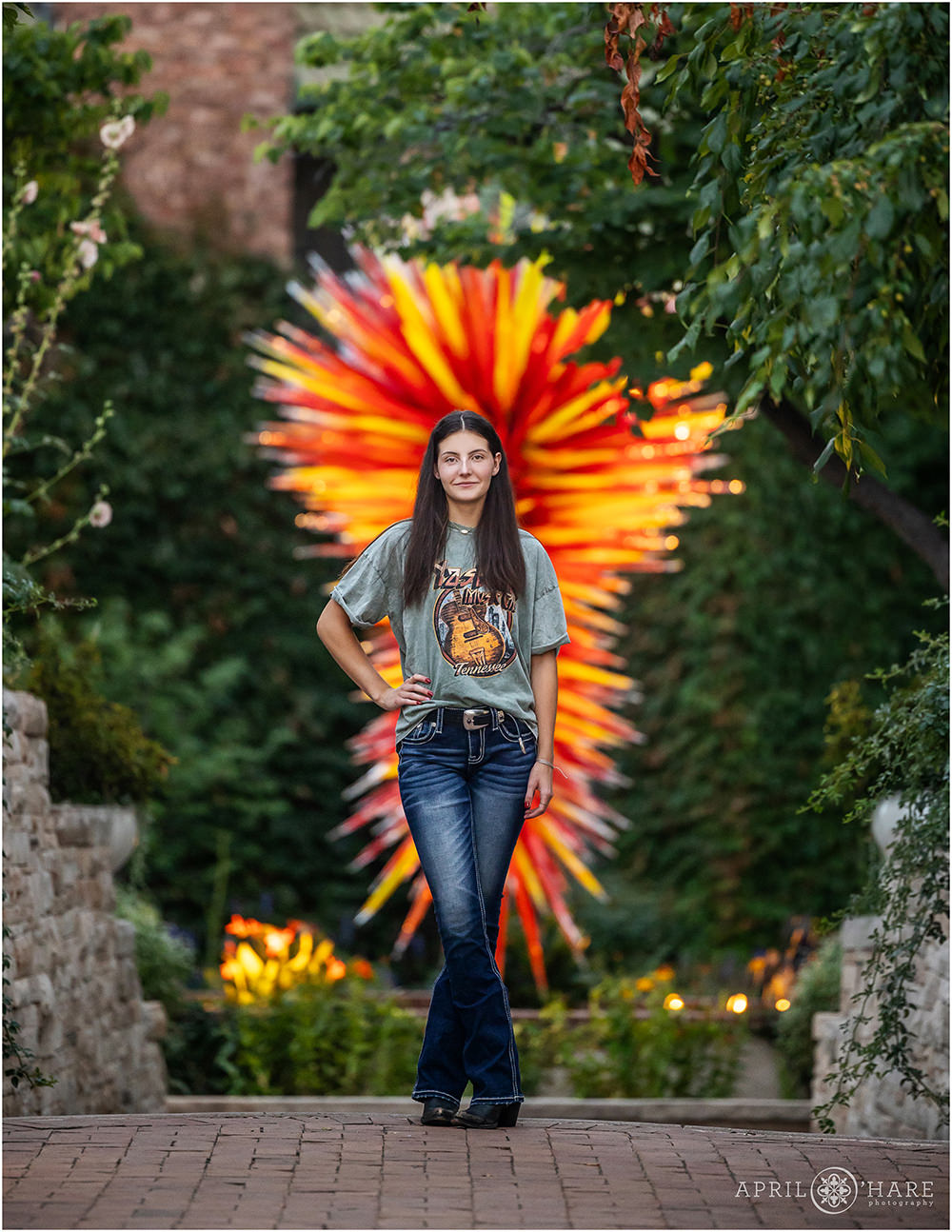 Unique senior portrait in front of the red and yellow Chihuly sculpture at Denver Botanic Gardens