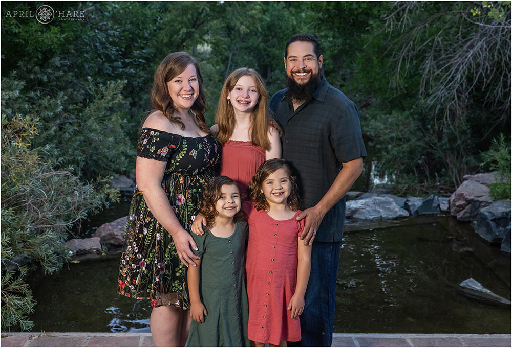 Family pose for a photo together in front of the stream at James Bible Park in Denver CO