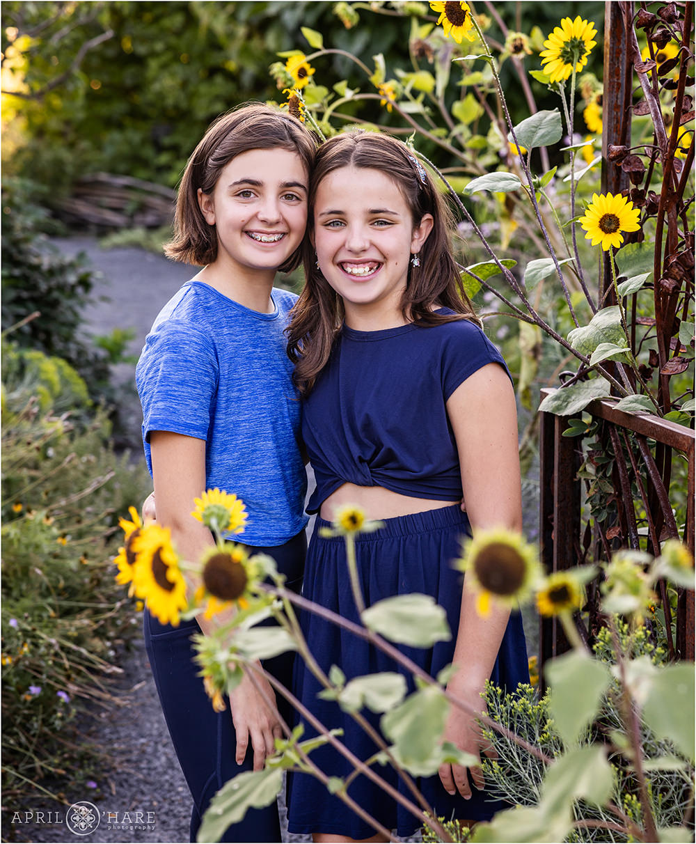 Two young sisters pose for a portrait together with the sunflowers at Denver Botanic Gardens
