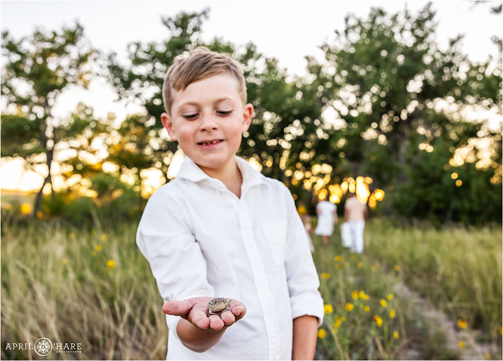Young boy holding a toad in his hand at his family photoshoot in Parker Colorado