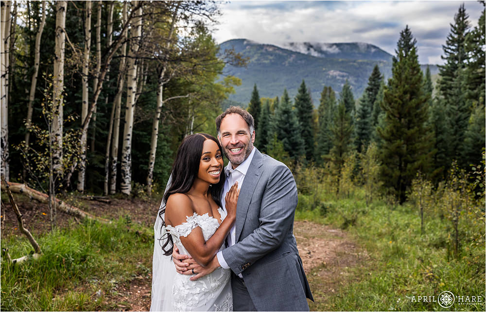 Beautiful couples photo in wedding clothing in an aspen tree meadow with a mountain backdrop in Evergreen Colorado