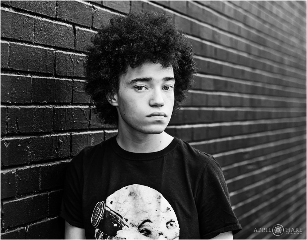 B&W Photo of a teen in front of a black brick wall on South Broadway in Denver CO
