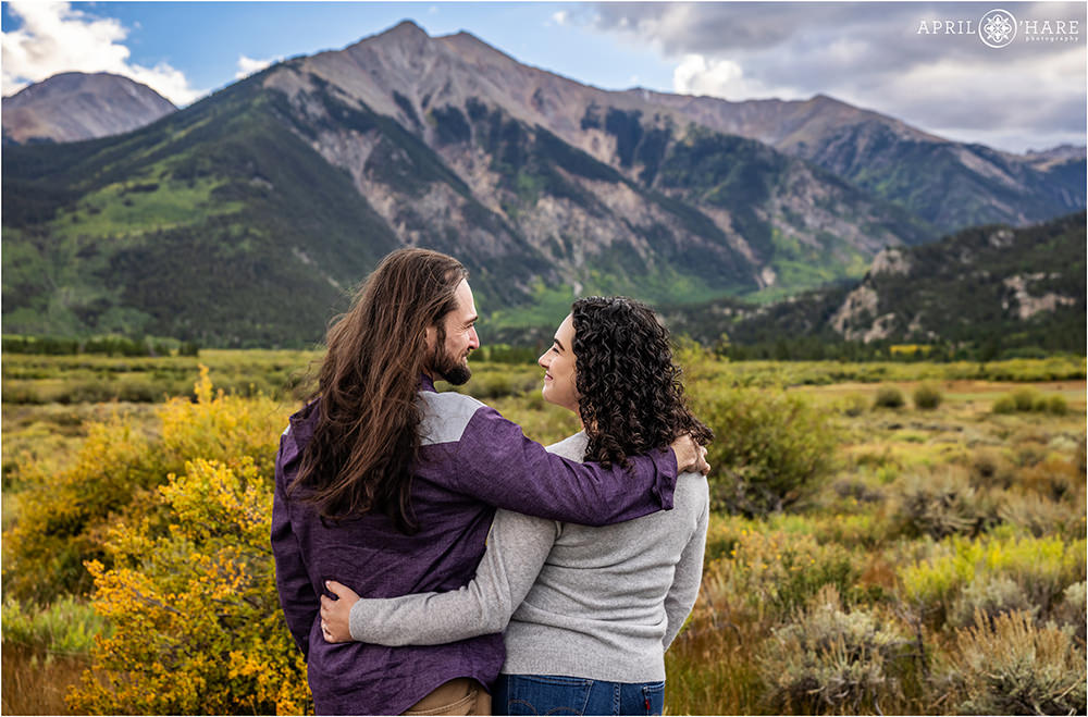 Couple looks into each other's eyes as they stand before a majestic mountain view at the Twin Lakes Historic District in Colorado