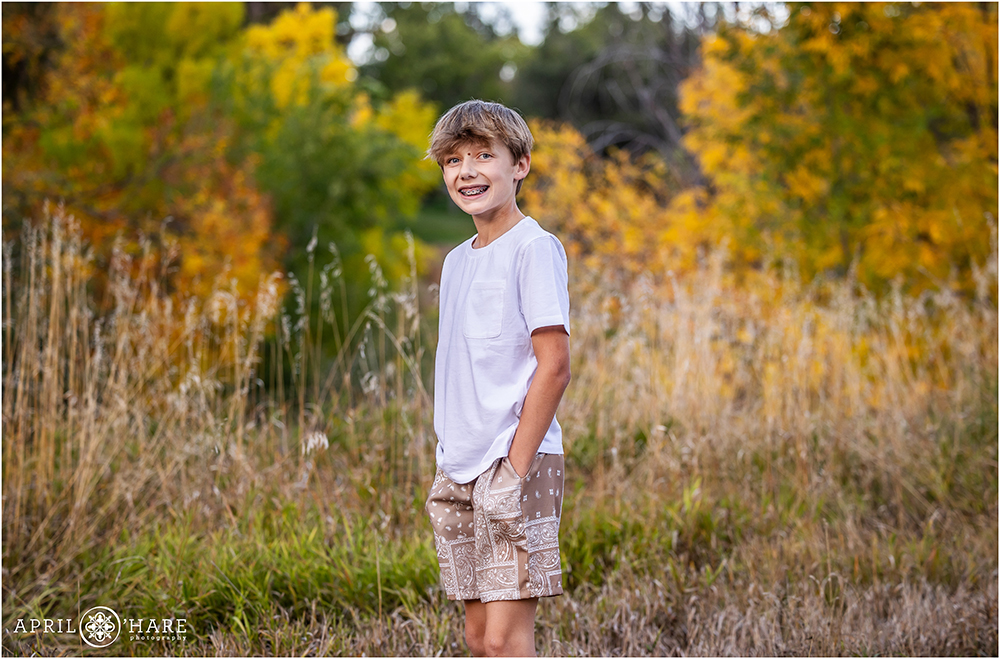 Cute kid wearing a white tshirt in front of a pretty fall color spot near his home in Littleton CO