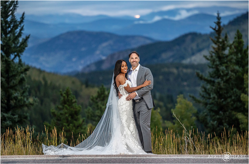 Wedding couple pose with a pretty mountain backdrop on Squaw Pass Road in Evergreen Colorado