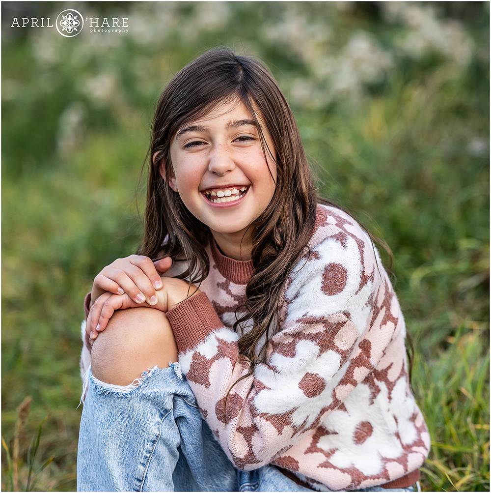 Adorable girl wearing ripped jeans and a flower sweater at her family session near her home in Littleton CO