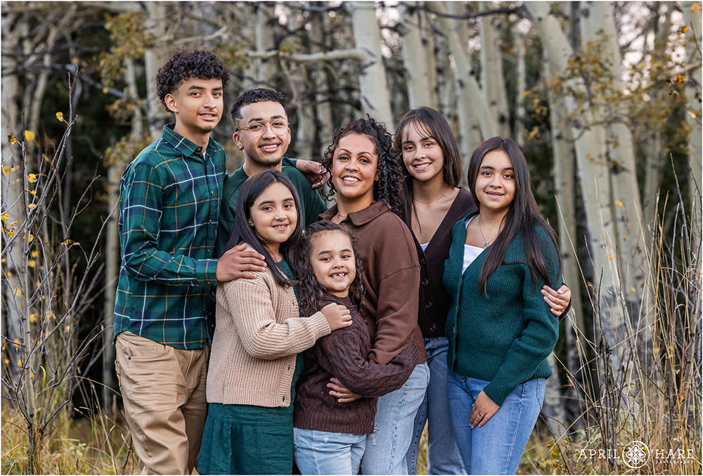 Cute family photo with 6 kids pose together in the woods with aspen tree backdrop in Evergreen Colorado