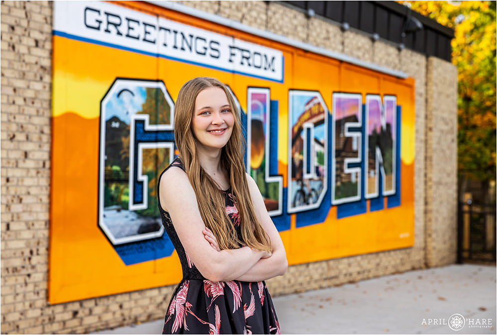 Cute photo of a high school senior girl in front of the "Greetings from Golden" mural along Clear Creek