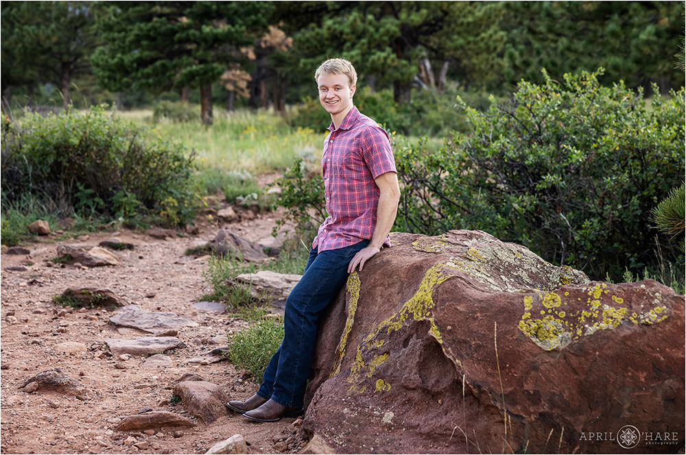 Senior boy leans up against a rock at Shanahan Ridge Trailhead in Boulder CO