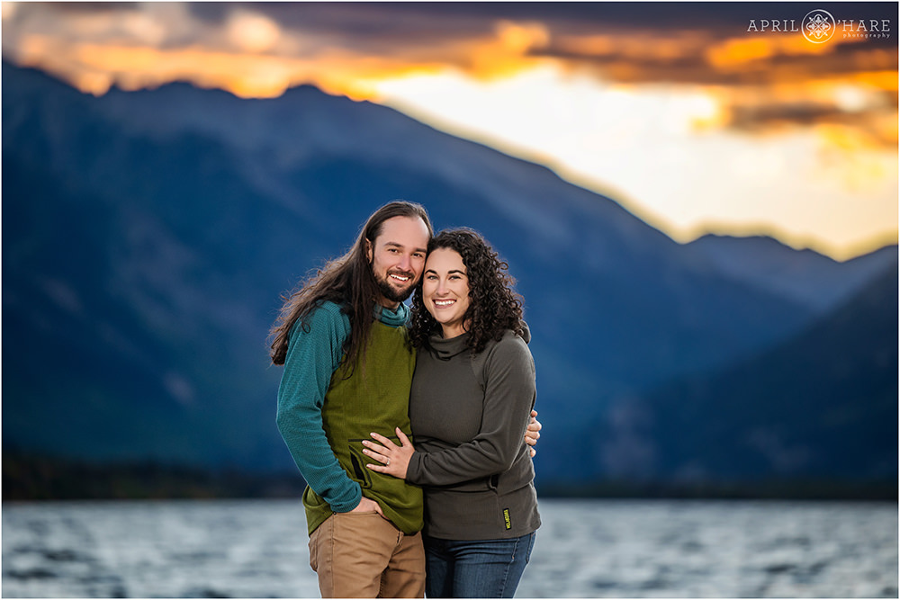 Beautiful orange sunset backdrop with blue mountains for an engagement photo in Colorado