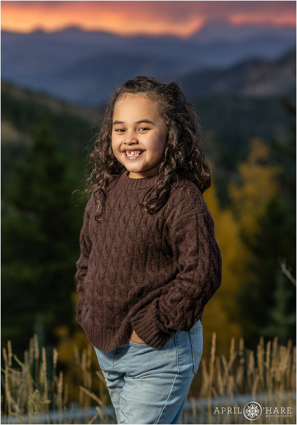 Cute girl wearing a brown sweater at sunset with a mountain backdrop on Squaw Pass Road in Evergreen CO