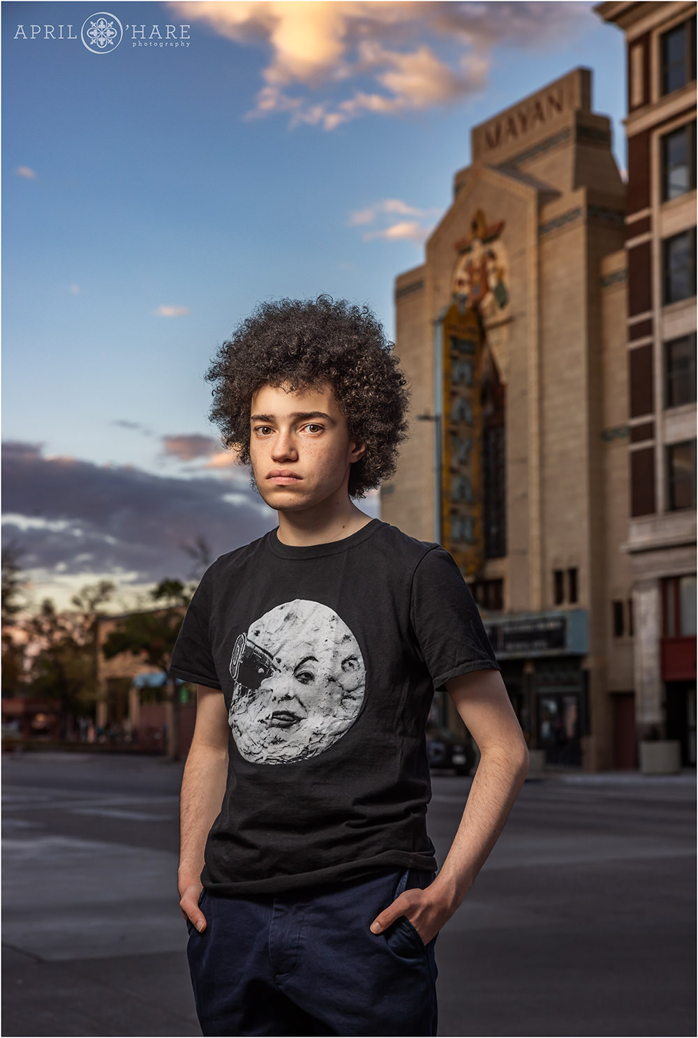 Historic Mayan Theater at sunset for a senior portrait of a young man wearing a black Georges Méliès tshirt