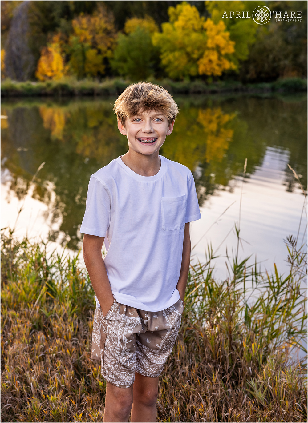 Young boy wearing shorts and a white tshirt on a pretty fall color day near his house in Littleton CO