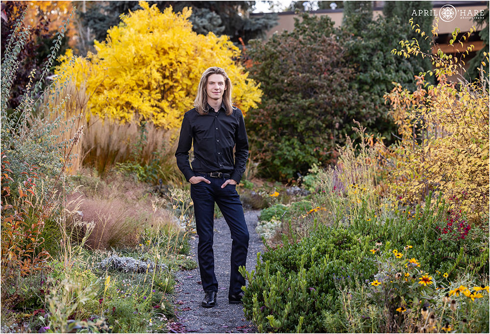 Fall garden senior portrait for a young man wearing black button down shirt with dark navy blue jeans at Denver Botanic Gardens