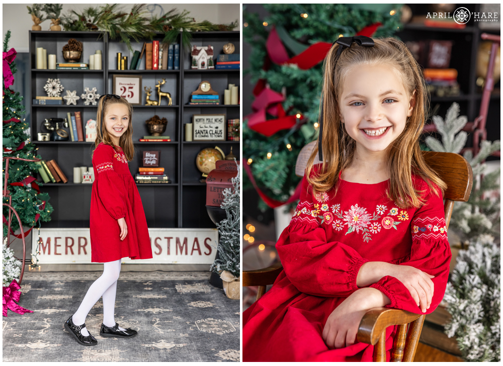 A girl wearing a pretty embroidered red dress poses for photos at her family's Christmas portrait session at a studio in Denver Colorado