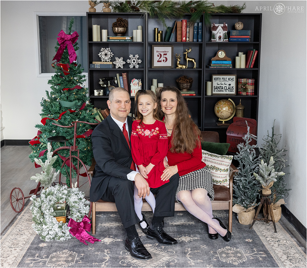 Family of Three pose together at their indoor family photoshoot with a Christmas library theme