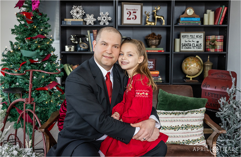Dad with his daughter in an indoor studio with a Christmas library backdrop