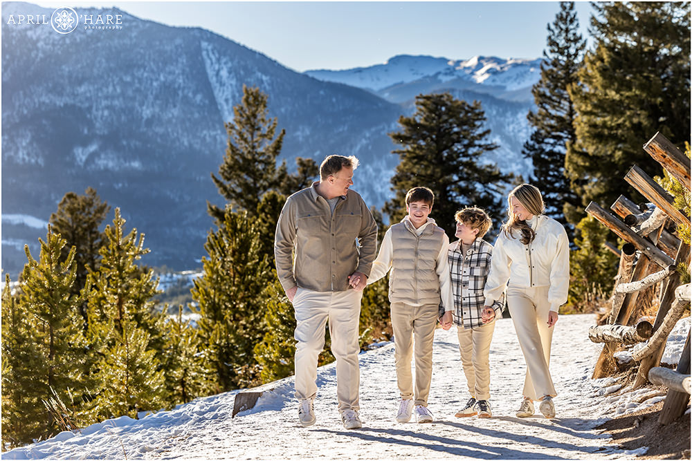A family of four hold hands as they walk down the snowy path at Sapphire Point on a bright sunny Colorado day