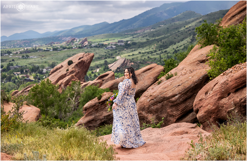 Bride twirls her pretty floral blue and white dress in the scenery of the red rocks landscape on her spring wedding day in Morrison