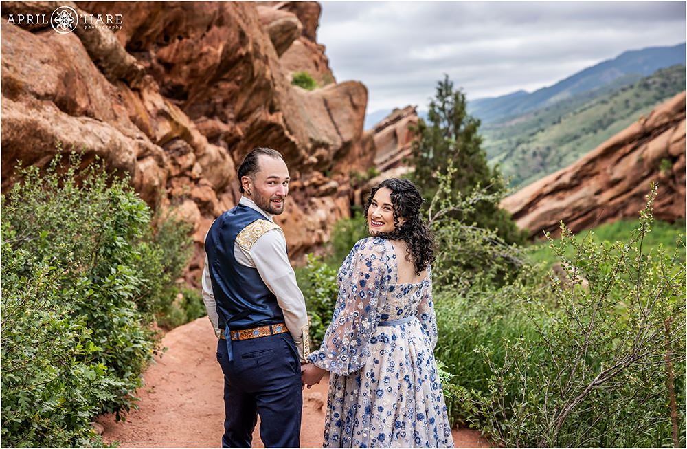 Adorable photo of a couple walking along a trail surrounded by red rock formations on the Trading Post Trail in Colorado