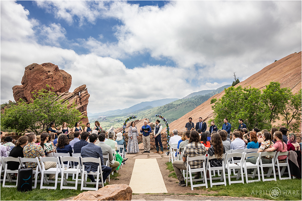 Wide angle photo of a couple at their wedding ceremony at Red Rocks Trading Post Backyard in Morrison, CO