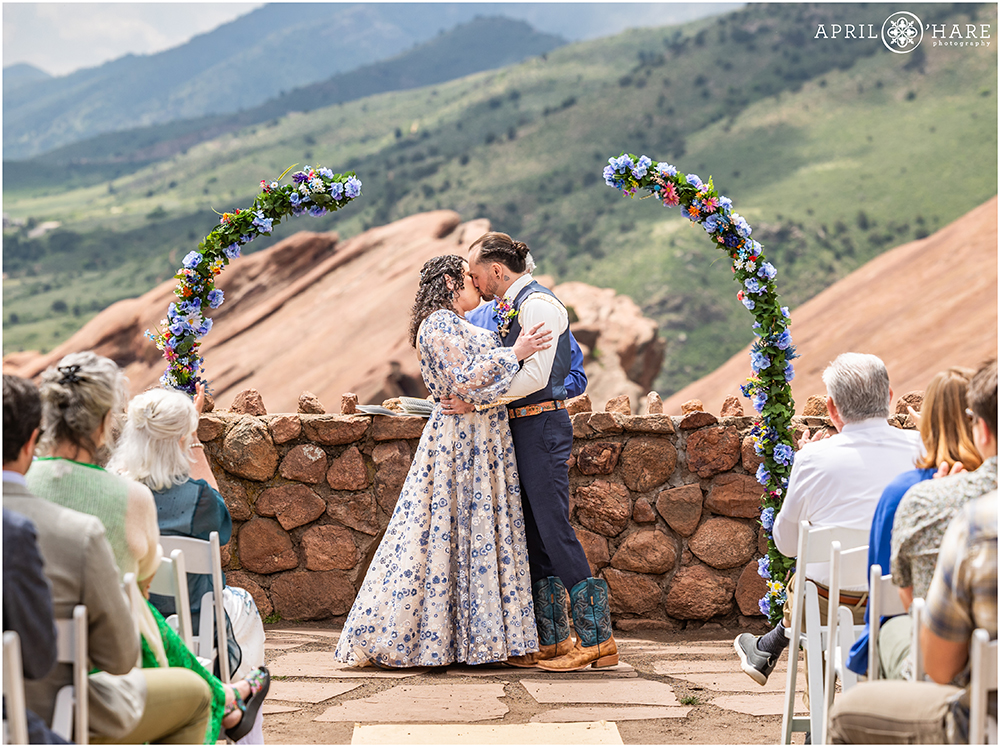 Bride and Groom Kiss at the end of their outdoor wedding ceremony at the Red Rocks Trading Post Backyard in Colorado