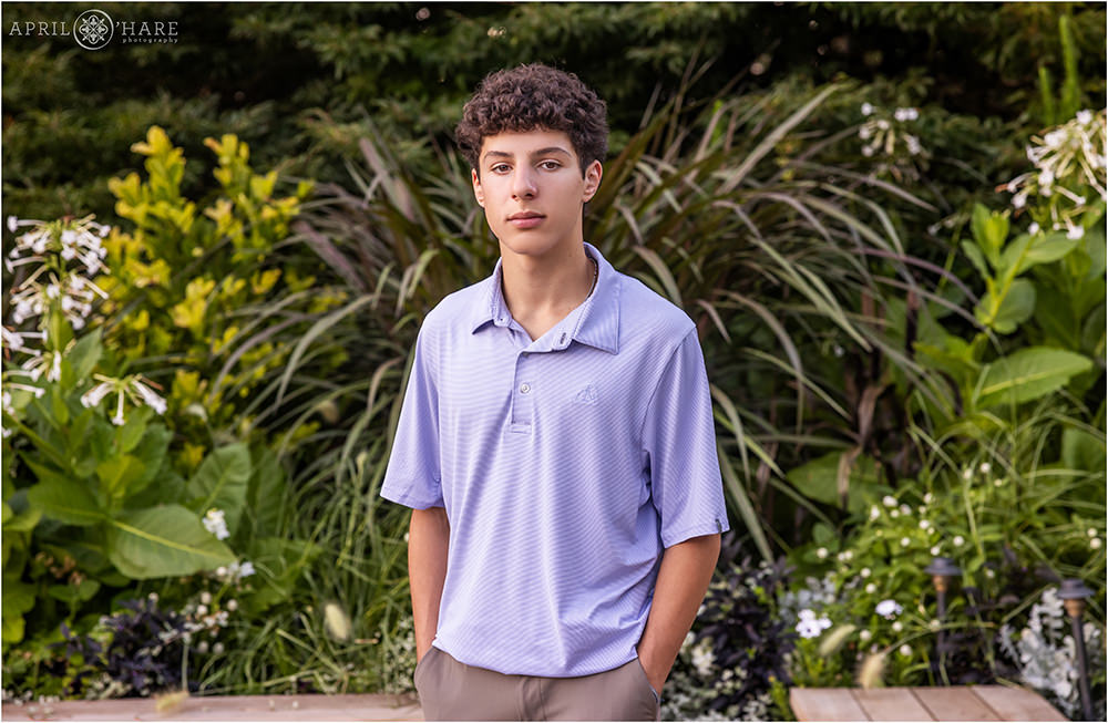 Serious expression for a high school senior boy in front of green plant backdrop at Denver Botanic Gardens