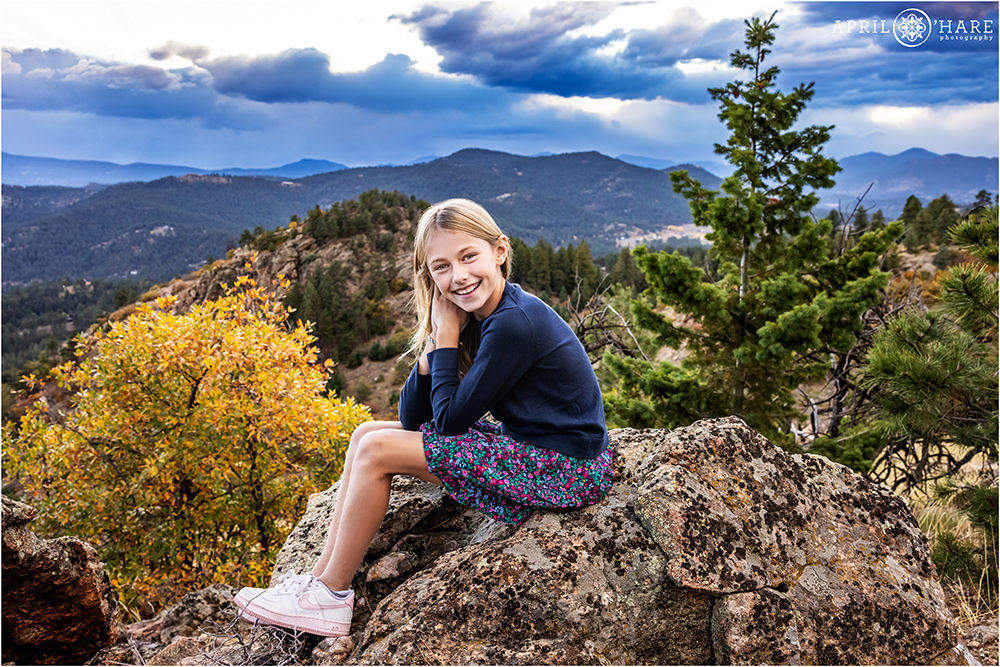 Girl sits on a rock at her family photoshoot at West Mount Falcon in Colorado