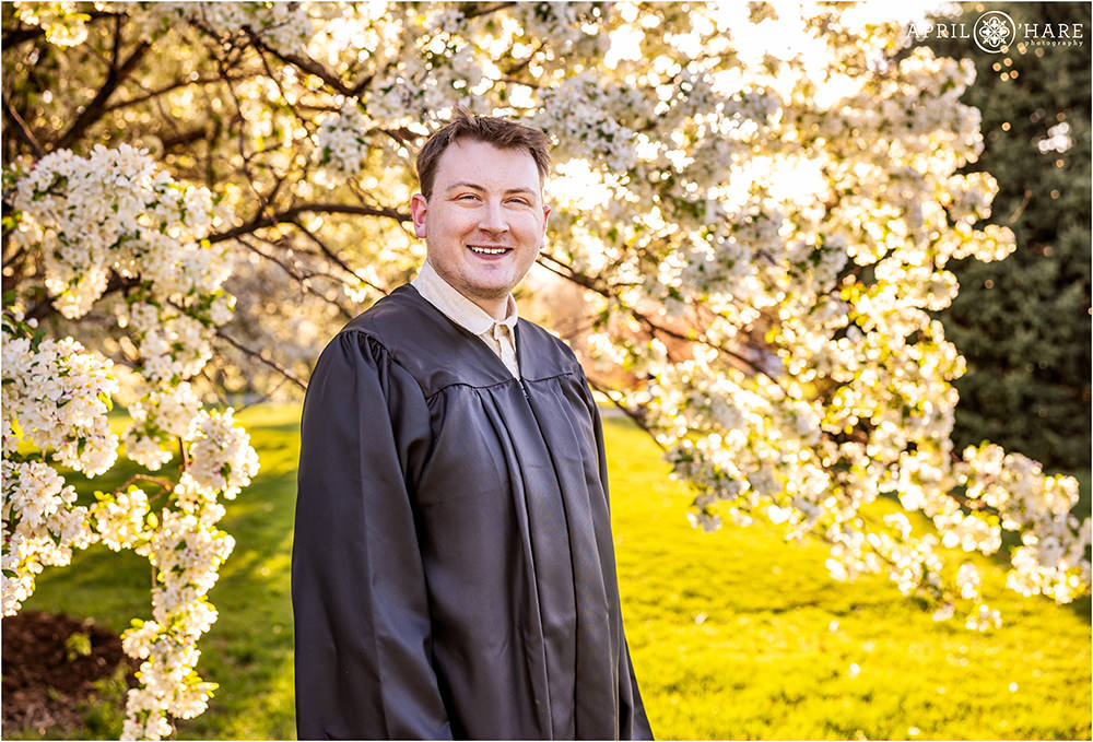 Graduation headshot photo on a bright spring day with tree blossom backdrop at City Park in Denver