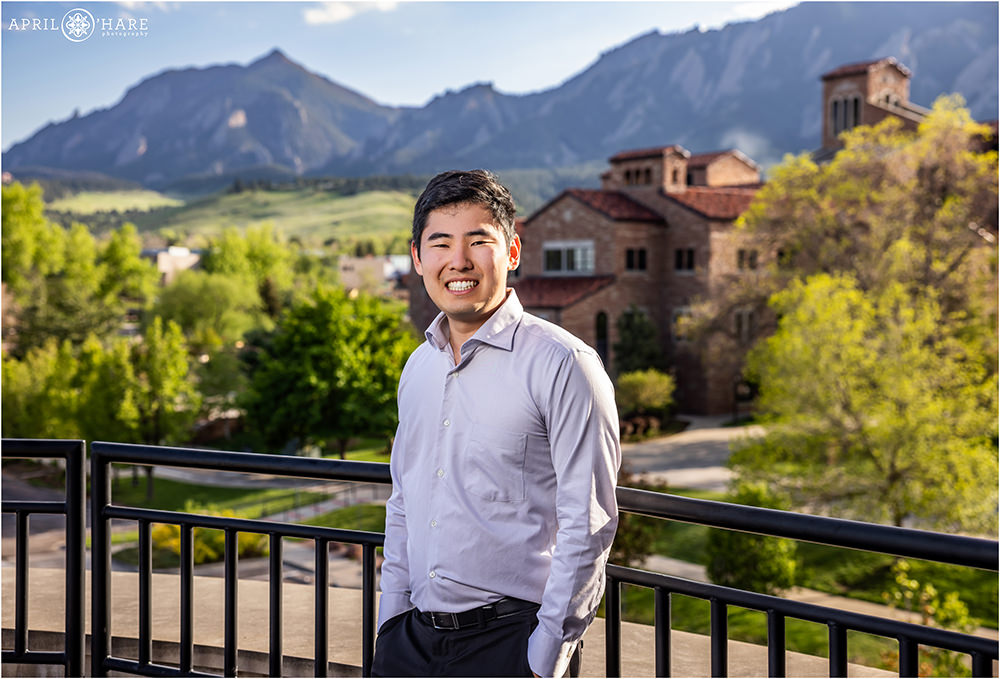 A young man gets graduation photos at Koelbel Hall at the University of Colorado in Boulder