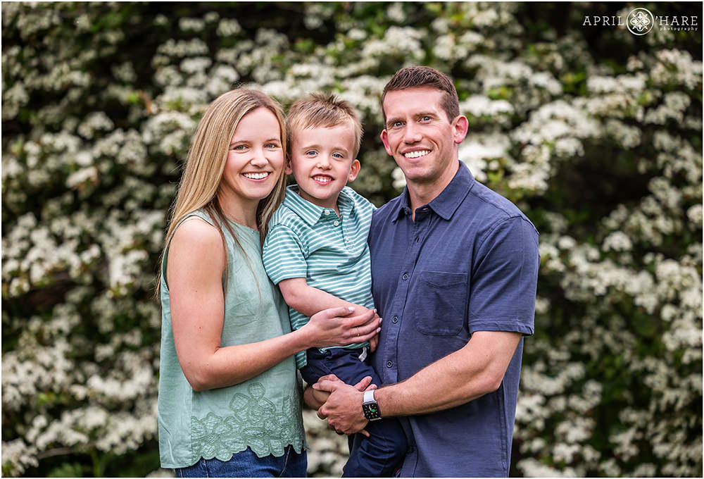 Beautiful photo of a family of three with floral backdrop during spring at City Park in Denver CO