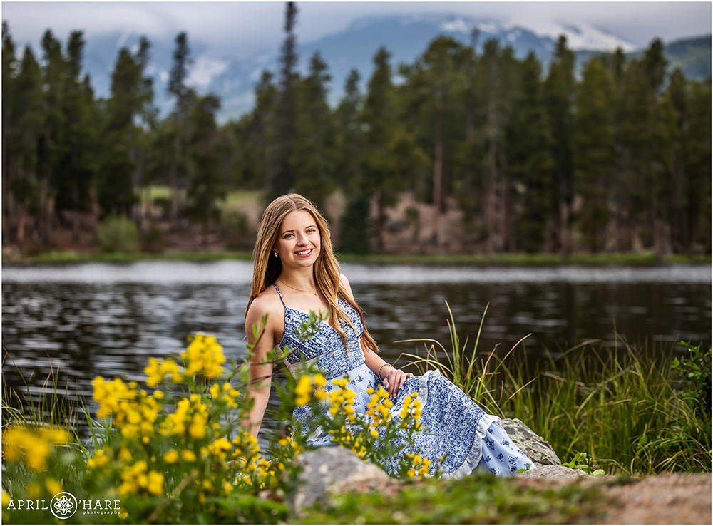 Sprague Lake senior photo at Rocky Mountain National Park during June with pretty yellow wildflowers in the foreground