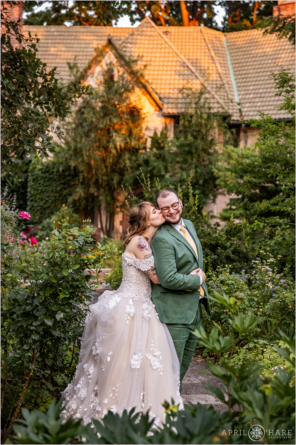 Sweet photo of a bride kissing her groom on the cheek on their wedding day with Richard Crawford Campbell House in the backdrop at sunset