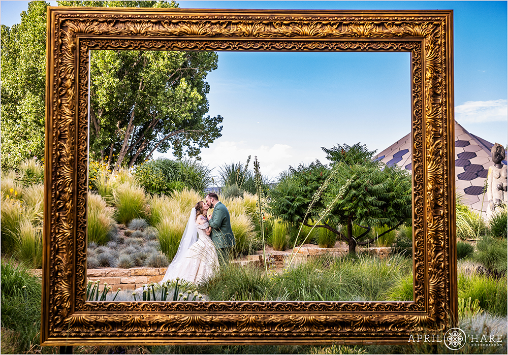 Gold Ornate Picture frame art sculpture frames a kissing bride and groom on their wedding day at Denver Botanic Gardens