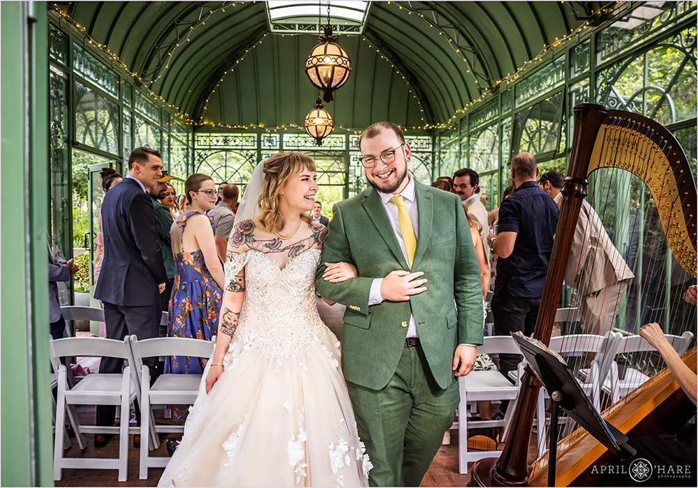 Happy couple walk out of their wedding ceremony at the Woodland Mosaic Solarium at Denver Botanic Gardens