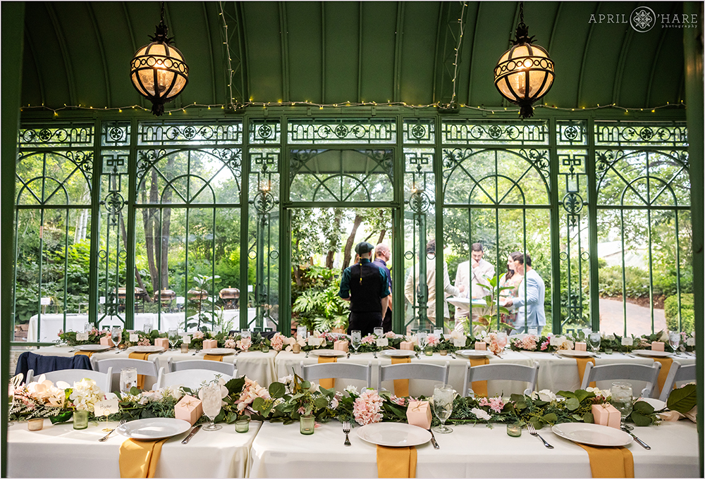 Summer wedding reception dinner with two long tables set up inside the Woodland Mosaic Solarium at Denver Botanic Gardens