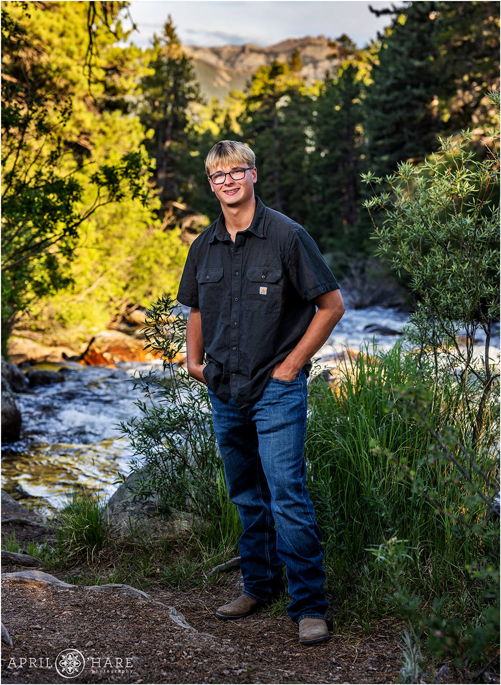 High School Senior Boy stands next to the river at his senior photoshoot at Rocky Mountain National Park