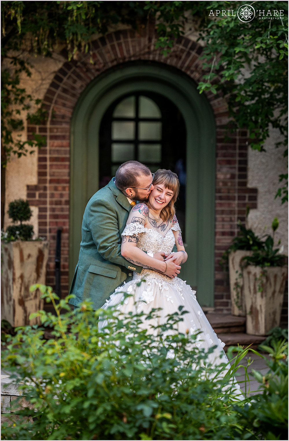 Cute candid photo of a couple snuggling on their wedding day in the oval garden at Denver Botanic Gardens