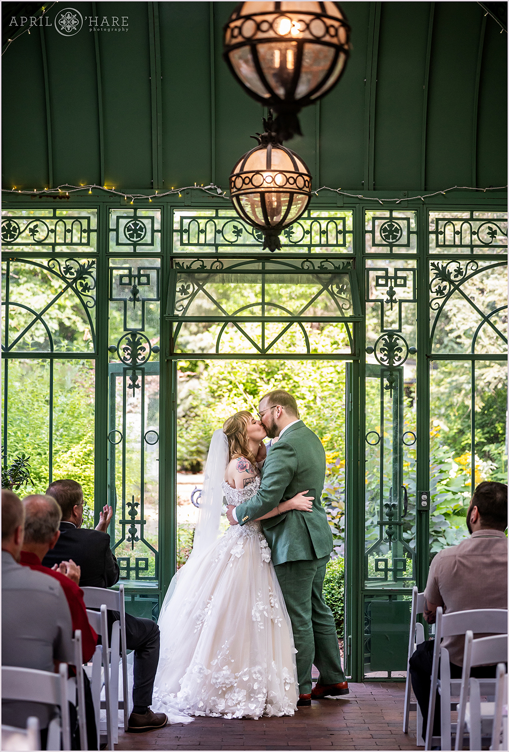 Couple kiss at their wedding ceremony at Denver Botanic Gardens Woodland Mosaic Solarium